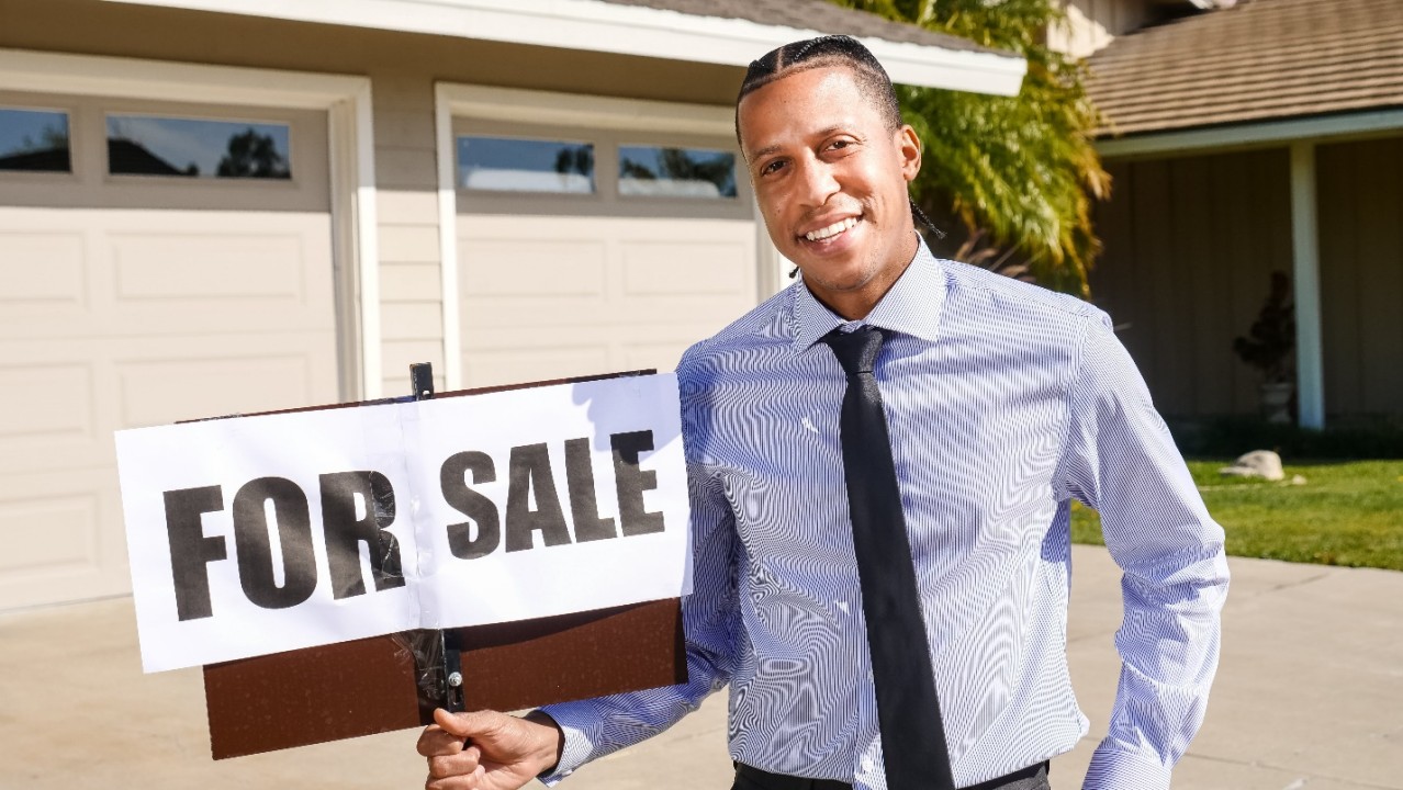 Realtor Holding a ‘For Sale’ Sign